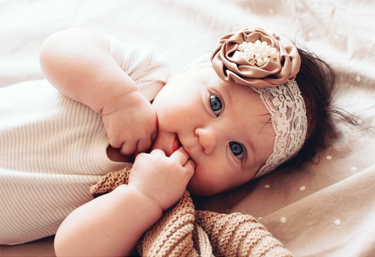 Baby girl with a white lace head band.