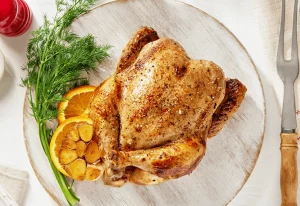 Hot roast chicken on a plate with roasted garlic.