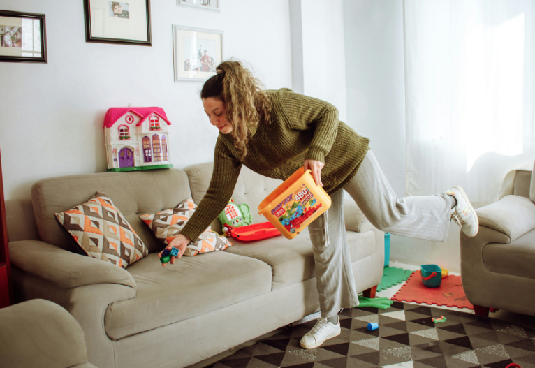 mum picking up toys from couch